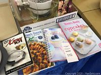 Four baking cookbooks displayed including recipes for cupcakes and desserts, alongside GT Express Meal Maker cookbook