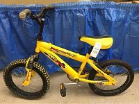 Side view of a yellow kids bicycle showing the entire bike with knobby tires, yellow padded seat, and handlebar.
