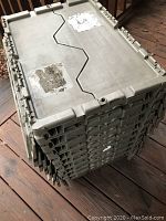 Nine stacked extra large gray plastic storage tubs with interlocking lids showing top view with some tape residue and wear marks.