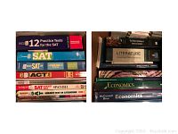 Top view of stacked textbooks and test prep books including SAT and ACT preparation guides, literature and economics textbooks.