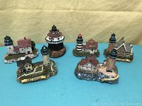 Full view of all six lighthouse figurines displayed on a blue surface with yellow backdrop