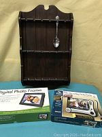 Wooden spoon rack with one silver spoon and two boxed electronic photo frames.