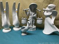 All five ceramic decor figurines grouped, showing angel, swans, man with buckets, and duck