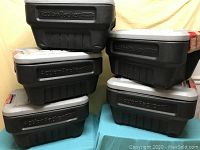 Five stacked black Rubbermaid Action Packer tubs with gray lids and red locking clips, showing the overall condition and quantity of the tubs.