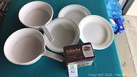 Four white Corelle bowls and two white Corning skillets on table