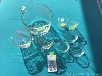 Top view of eight assorted Pyrex measuring cups, mixing bowls, and small bowls arranged on blue surface with measurement markings visible.