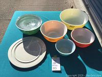 Full set of mixing bowls and plates displayed on table showing size variety and colors.