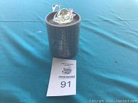 Swarovski crystal swan figurine atop original branded round box with teal fabric background.