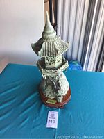 Front view of an antique hand-carved Asian stoneware pagoda sculpture on a wooden base.