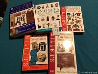 Lot of five antiques and collectables price guide books on a blue surface.