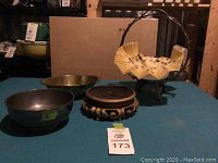 Five-piece lot on blue cloth showing various decorative bowls and stands, including yellow perforated dish on basket stand and wooden carved stand