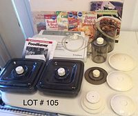 Photo showing white FoodSaver vacuum sealer with hose attachment, two black square storage containers with lids, several round container lids, two cookbooks, and four cooking magazines.