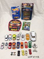 Photo shows a collection of assorted pre-owned Hot Wheels and Matchbox cars, including boxed cars, loose cars, a keychain car, and some loose car parts like wheels and axles.