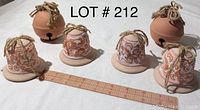 Photo shows 6 clay bells, 4 decorated and 2 plain on white background with ruler for size reference.