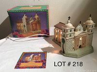Photo showing the lit ceramic model of Santa Barbara Mission along with its box and informational card.