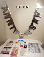Silver metallic banners spelling 'HAPPY BIRTHDAY' and 'ANNIVERSARY' hanging on wall with assorted small party decoration items on table.