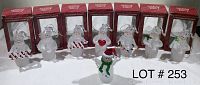 Photo showing eight white plastic snowmen Christmas ornaments in original packaging six in boxes and two outside, each with different accessories such as candy canes, scarves, hearts, and holly leaves.