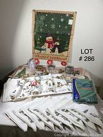 Full lot of assorted Christmas-themed textiles including placemats, hand towels, napkins, a small Christmas fabric wall hanging featuring a snowman, and a package of green cleaning cloths.