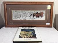Framed print by Bev Doolittle with a wooden frame, a horse and snowy forest scene visible, and a book titled 'Camouflage' by Elise Maclay in front.