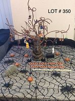 Photo of Halloween decoration lot featuring central witch tree with hanging mini pumpkins and figurines, small plush rat, orange pumpkin decorations, all arranged on spiderweb patterned fabric.