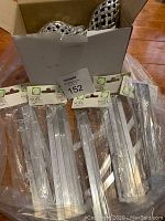 Box containing multiple clear, elongated icicle-style Christmas ornaments in original packaging labeled 'Noel', showing brand and packaged condition.