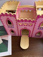 Melissa & Doug wooden castle playset, pink color with heart decorations on walls and windows, wooden bridge attached