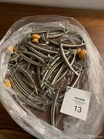 Top-down photo showing assortment of metal curved cabinet handles with screws, metal and wooden round knobs in plastic-wrapped container.