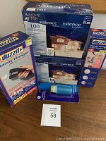 Photo showing two boxes of Holiday Time valance Christmas lights and two Duzzit branded packages including a Handy Hanger 20 piece pack and a box of hooks.