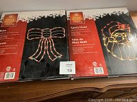 Packaging of Bow and Santa Head lighted Christmas decorations by Home Accents Holiday, showing front and details on the included items.