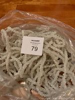 Plastic bag filled with coiled white sparkling garland strands lying on the floor.