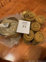 Six pieces of fabric garland, rolled, some wrapped in metallic twist ties, placed on wooden floor.