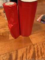 Two upright red ribbon rolls on wood floor