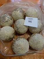 Lot of eight assorted glittery Christmas ball ornaments in silver, white, and dark glitter colors, placed in plastic bag.