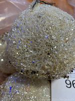 Close up view of a single glitter-covered spherical ornament showing fine glitter and sequins.