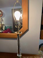 Full view of lamp lit to show structure and harp with exposed bulb.