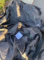 Three black fabric tire storage bags shown laid out flat outdoors, showing label pockets and handles.