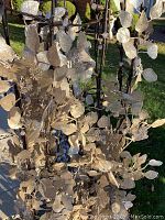 Close-up photo of the upper middle section showing silver metallic leaves and string lights attached to dark branches of the tree.