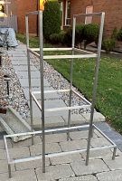 Full metal shelving frame standing outdoors on paving stones, showing overall structure and dimensions.