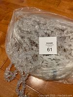 Clear plastic flower-shaped garland in bulk inside plastic bag, spread out on wooden floor