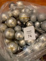 Full view of lot of silver, gray, and sparkly Christmas ball ornaments inside a plastic bag