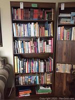Bookshelves filled with assorted fiction and self-help books, mainly paperbacks, well-organized.