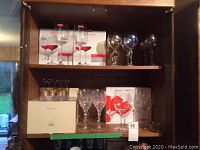 Overview of multiple shelves with boxes and various stemware including Spiegelau Capri and Crystal D'Arques glasses