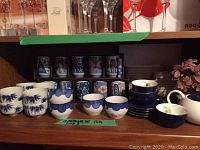 10 Japanese Hizen porcelain teacups and 6 additional blue and white teacups, shown on a shelf with traditional designs.