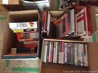 Top view of two cardboard boxes filled with books and DVDs, with visible spines showing some titles in Italian and English.