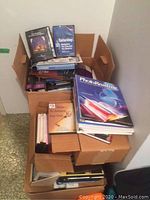 Boxes containing training manuals and DVDs stacked, showing titles like PhotoReading, Building Your Business, and Destination Saturday.