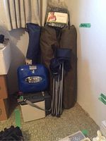 Grouped camping supplies including folding chairs, Pepsi cooler, travel cooler, ice chest, and bags stacked against wall.