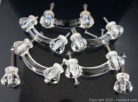 Curved and round vintage glass handles with metal bases arranged on black reflective surface.