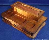 Front view of wood and leather desktop organizer showing drawer with leather inset and recessed compartments on base.