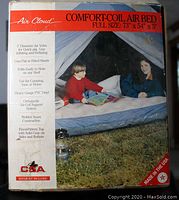 Box front packaging of Air Cloud Comfort-Coil Air Bed showing the image of air bed inside a tent with a child and woman, along with feature list and dimensions.