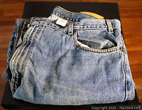 Used Levi's jeans folded on black surface, showing typical denim wear.